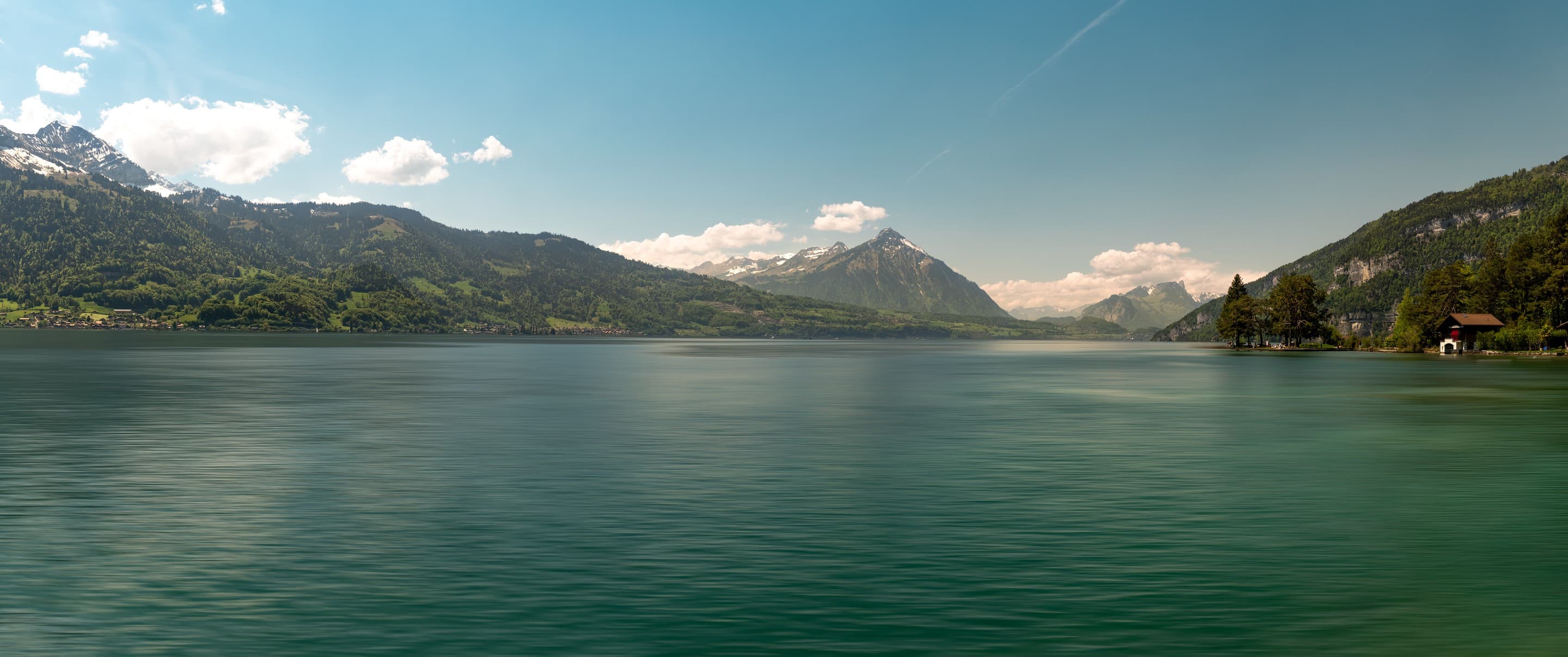 Cinematic aerial landscape of a turquoise alpine lake surrounded by the Swiss Alps